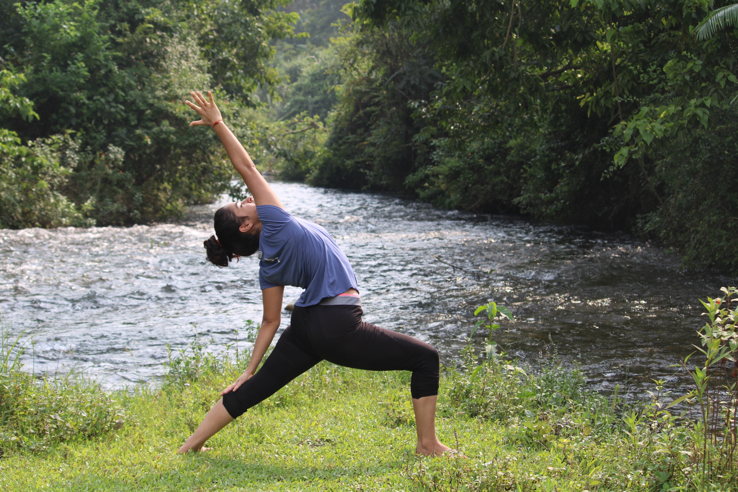 A practitioner in a calm, grounded yoga stretch beside a quiet river