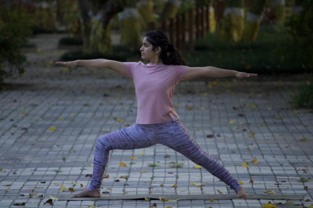 Practitioner in a standing prenatal-friendly warrior stretch outdoors